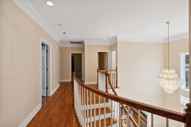 hall with a notable chandelier, plenty of natural light, crown molding, and dark wood-type flooring