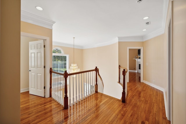 hall with a notable chandelier, ornamental molding, and wood-type flooring