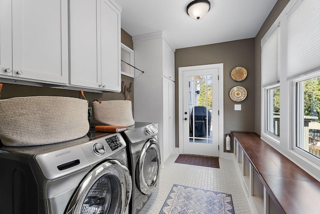 clothes washing area with cabinets and washing machine and clothes dryer