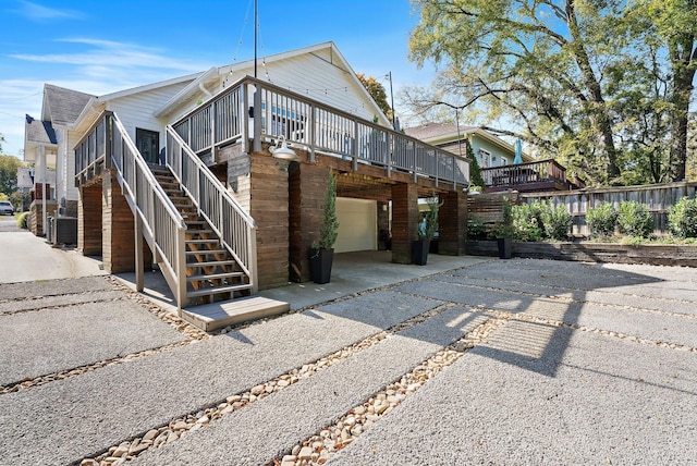 exterior space featuring a sunroom, central AC unit, a garage, and a wooden deck