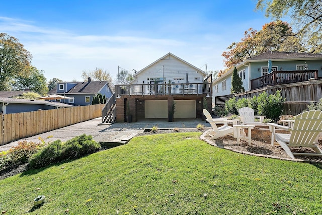 rear view of house featuring an outdoor fire pit, a yard, a garage, and a wooden deck