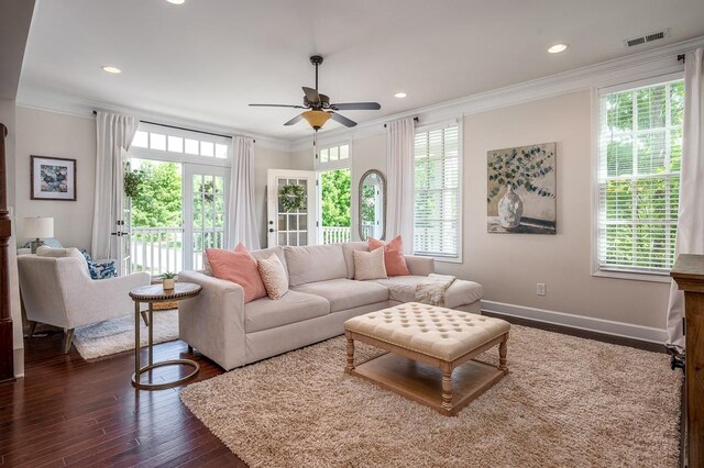 living room with dark hardwood / wood-style flooring, ceiling fan, and crown molding