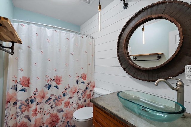 bathroom featuring toilet, vanity, wood walls, and curtained shower