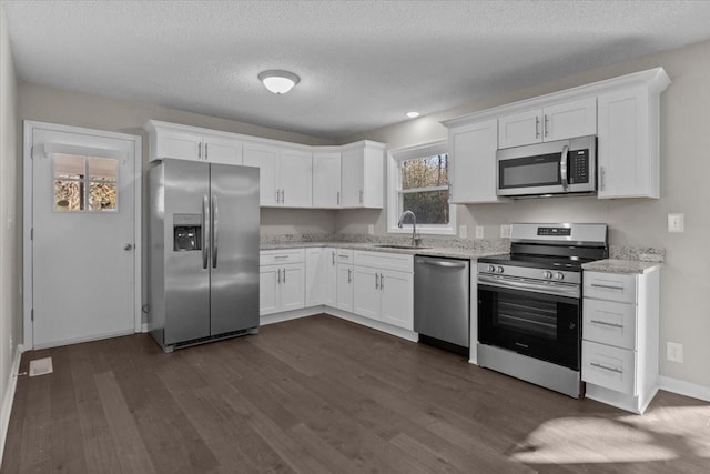 kitchen featuring appliances with stainless steel finishes, dark wood-type flooring, white cabinetry, and sink