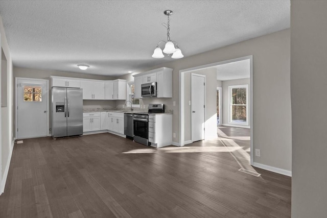 kitchen with sink, white cabinets, an inviting chandelier, pendant lighting, and appliances with stainless steel finishes