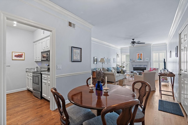 dining room featuring ornamental molding, light wood-type flooring, and ceiling fan