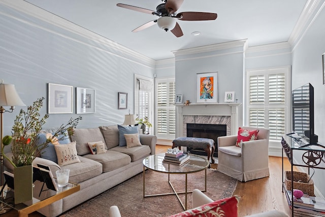 living room with a high end fireplace, ceiling fan, ornamental molding, and hardwood / wood-style flooring