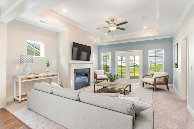 living room with ornamental molding, light hardwood / wood-style flooring, ceiling fan, and a tray ceiling