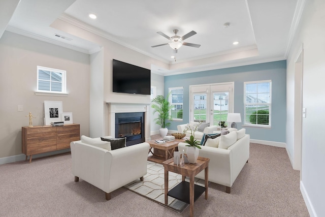 living room featuring ceiling fan, crown molding, light carpet, and a raised ceiling