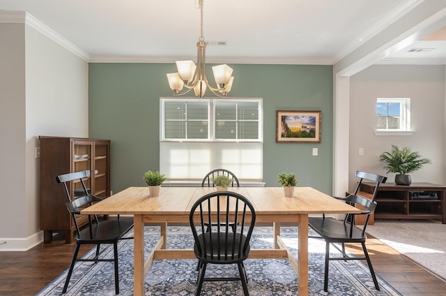 dining room with dark wood-type flooring, ornamental molding, and a chandelier