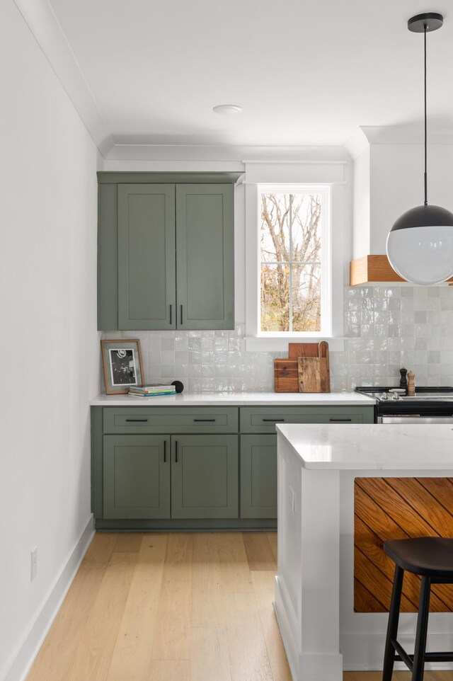 kitchen with green cabinets, crown molding, tasteful backsplash, and hanging light fixtures