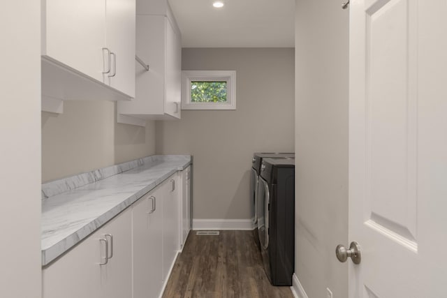 washroom with washing machine and dryer, cabinets, and dark hardwood / wood-style floors