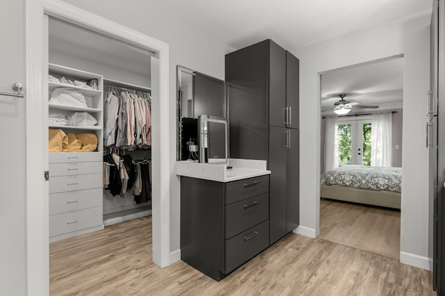 interior space with wood-type flooring, vanity, ceiling fan, and french doors