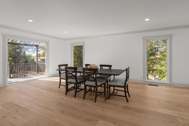 dining space with ornamental molding and light wood-type flooring