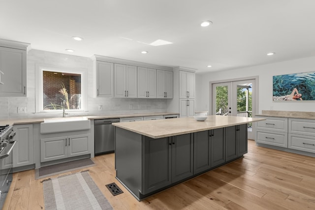 kitchen with gray cabinets, stainless steel appliances, a center island, french doors, and sink