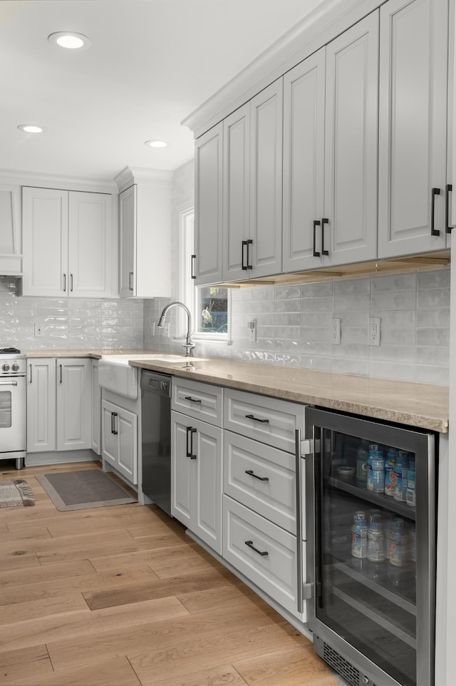 kitchen with light stone counters, light hardwood / wood-style flooring, range, wine cooler, and black dishwasher