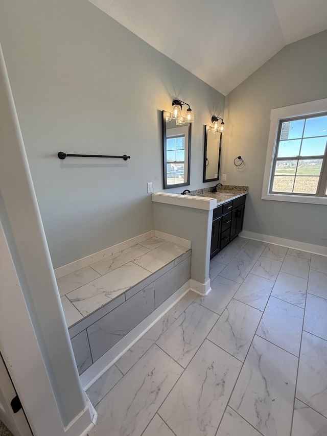 bathroom with a wealth of natural light, lofted ceiling, and vanity