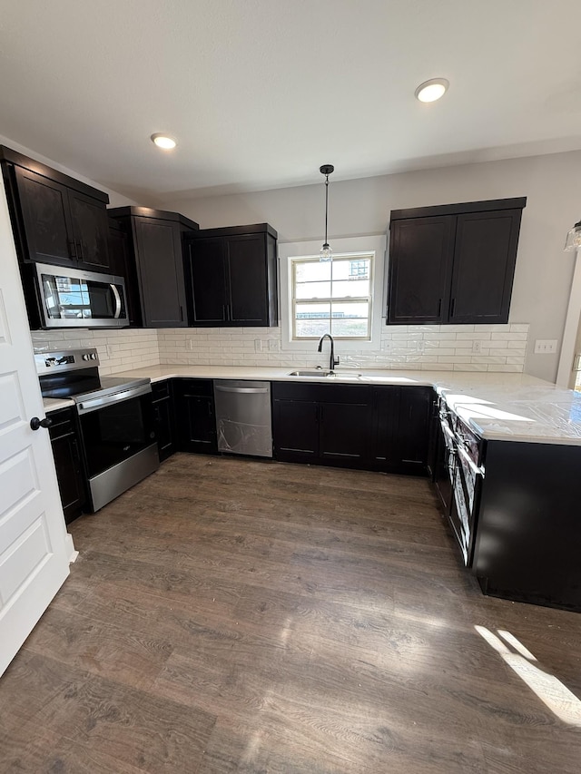 kitchen featuring stainless steel appliances, sink, decorative light fixtures, tasteful backsplash, and dark hardwood / wood-style floors