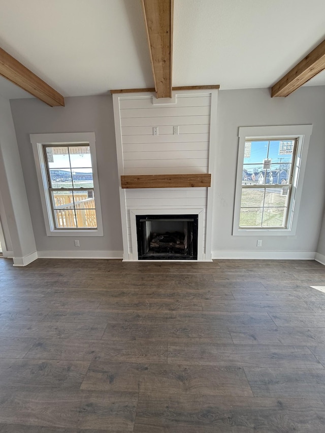 unfurnished living room with a large fireplace, dark hardwood / wood-style flooring, beamed ceiling, and plenty of natural light