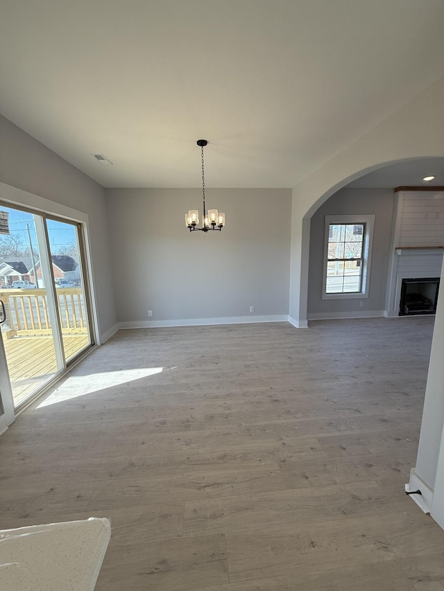 interior space with a large fireplace, a notable chandelier, and light wood-type flooring