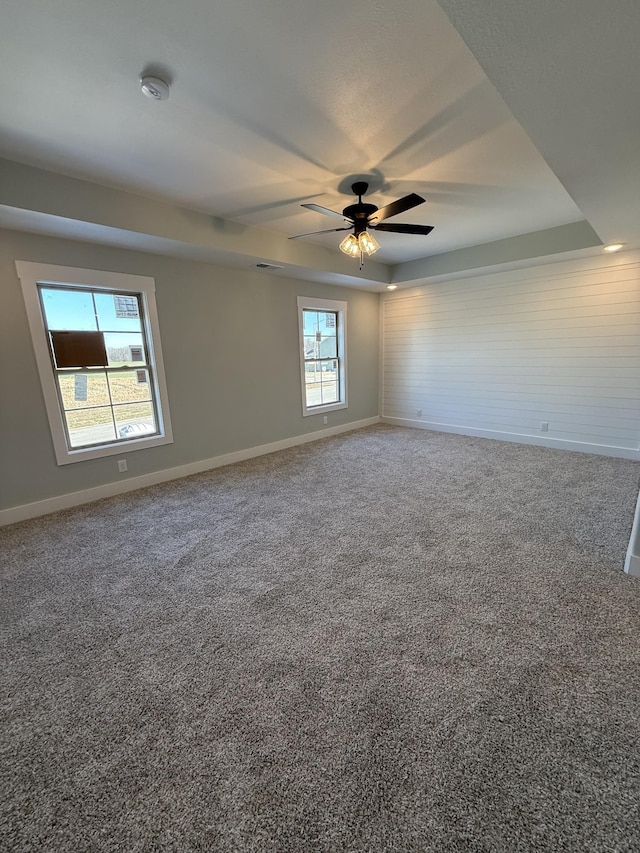 spare room with ceiling fan, carpet floors, plenty of natural light, and a tray ceiling