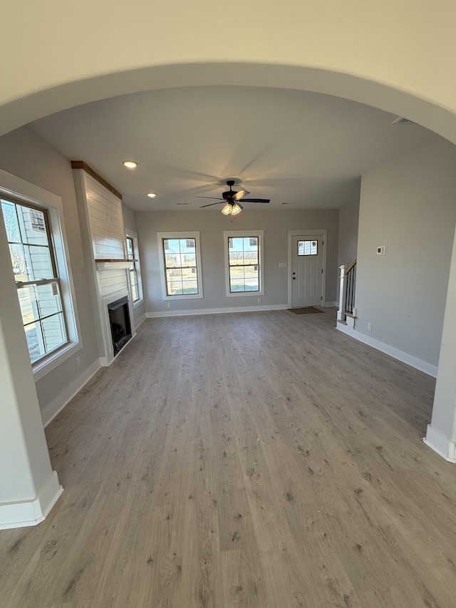 unfurnished living room featuring ceiling fan, a large fireplace, and light hardwood / wood-style floors