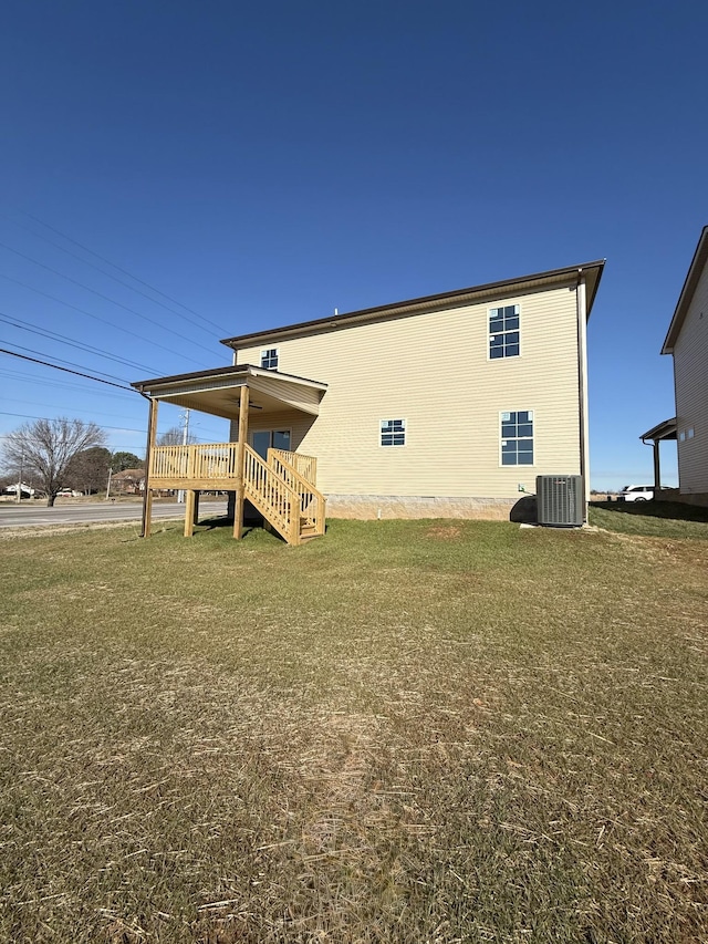 back of property featuring central air condition unit and a yard