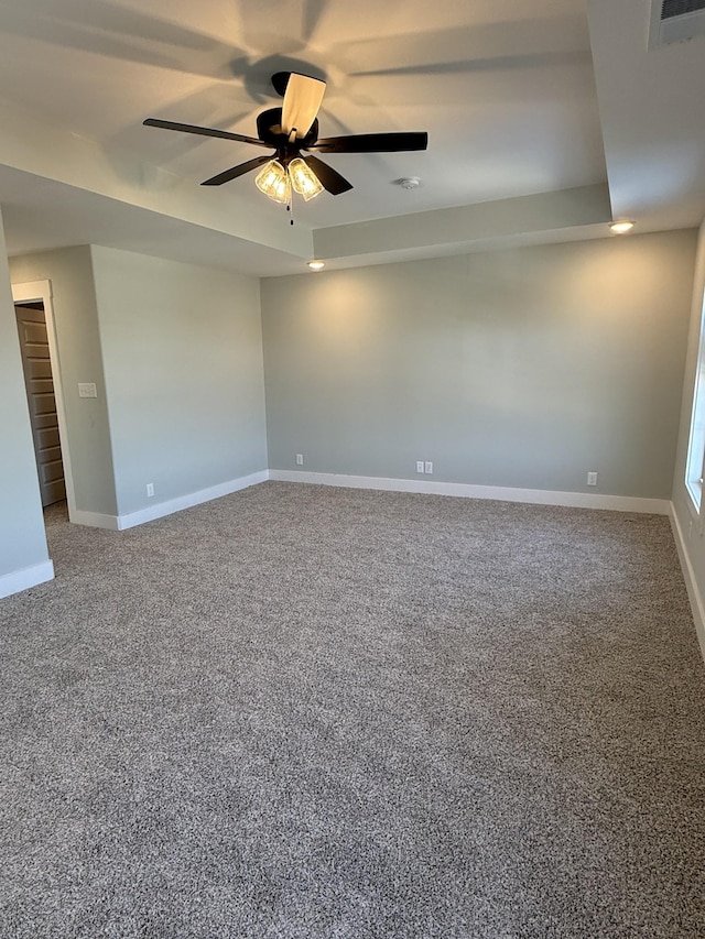 carpeted spare room featuring a raised ceiling and ceiling fan