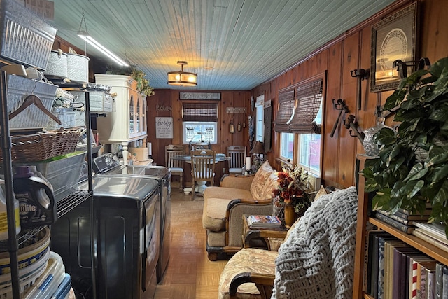 living room featuring washing machine and dryer, wooden walls, and dark parquet floors