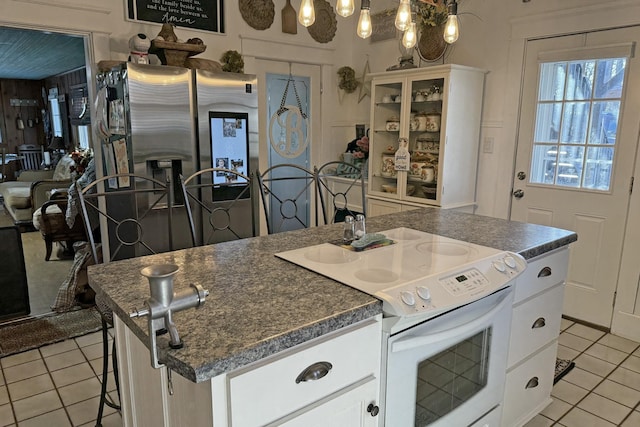 kitchen with light tile patterned floors, white cabinets, a breakfast bar, and white electric range oven