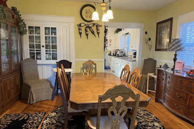 dining space with sink, light hardwood / wood-style floors, and a chandelier