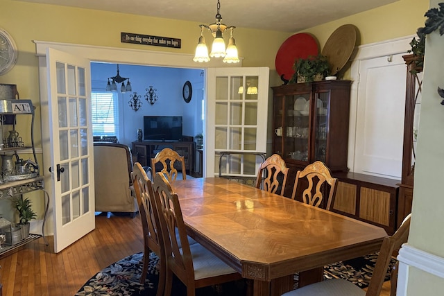 dining room with french doors, an inviting chandelier, and dark wood-type flooring