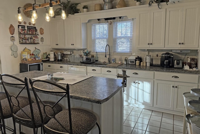 kitchen featuring decorative light fixtures, white cabinets, light tile patterned flooring, a breakfast bar area, and a kitchen island