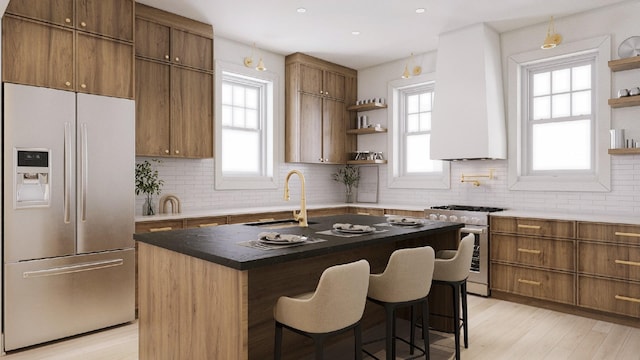 kitchen featuring stainless steel appliances, sink, an island with sink, custom exhaust hood, and decorative backsplash