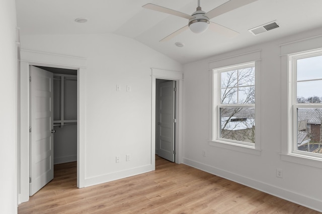 unfurnished bedroom featuring a closet, light wood-type flooring, ceiling fan, a spacious closet, and lofted ceiling