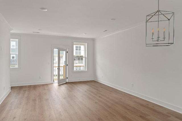 spare room with ornamental molding, a chandelier, and wood-type flooring