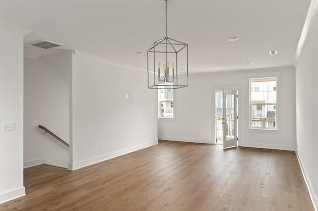 unfurnished dining area with ornamental molding, a chandelier, and hardwood / wood-style flooring