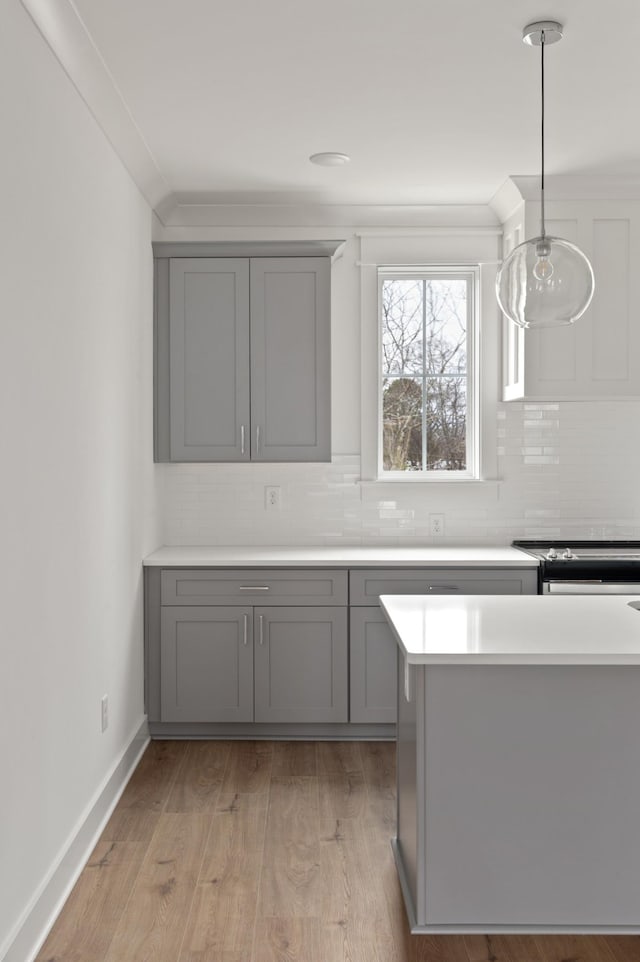 kitchen with hanging light fixtures, tasteful backsplash, light hardwood / wood-style flooring, and gray cabinets