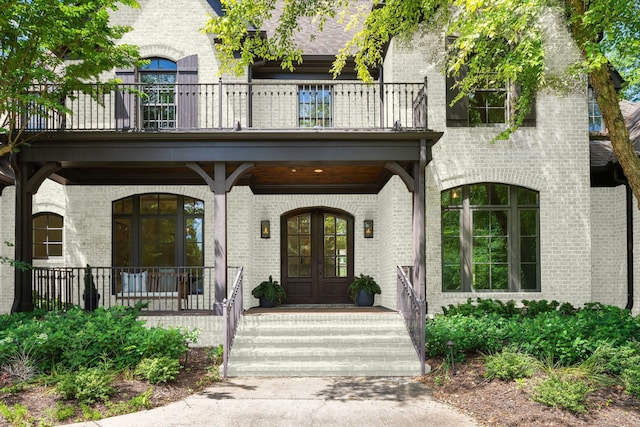 view of exterior entry featuring a balcony and french doors