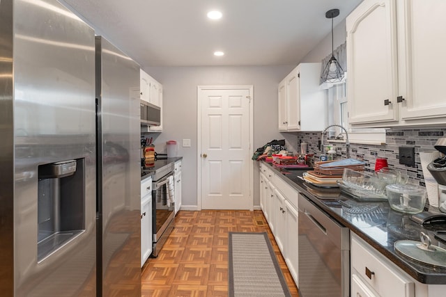 kitchen featuring appliances with stainless steel finishes, hanging light fixtures, sink, white cabinetry, and tasteful backsplash