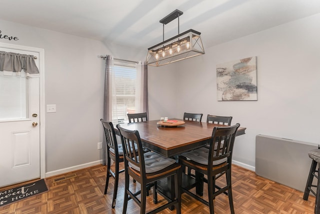 dining space featuring dark parquet flooring