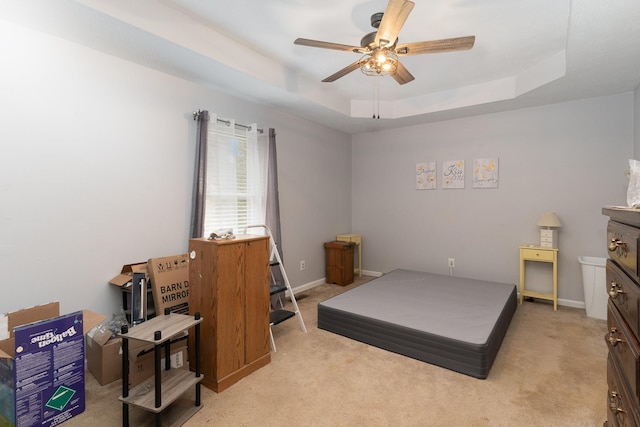 bedroom featuring ceiling fan, light colored carpet, and a tray ceiling