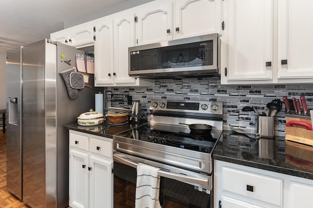 kitchen with white cabinetry, tasteful backsplash, dark stone counters, and appliances with stainless steel finishes