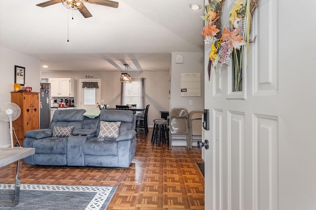 living room with ceiling fan, vaulted ceiling, and parquet floors