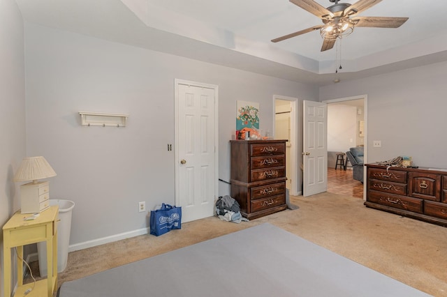 carpeted bedroom featuring ceiling fan and a tray ceiling