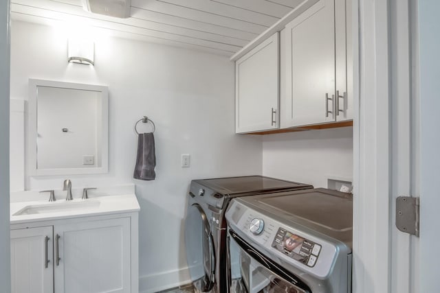 washroom with cabinets, sink, and independent washer and dryer