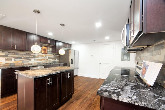 kitchen with dark stone countertops, a kitchen island, hanging light fixtures, dark wood-type flooring, and stainless steel appliances