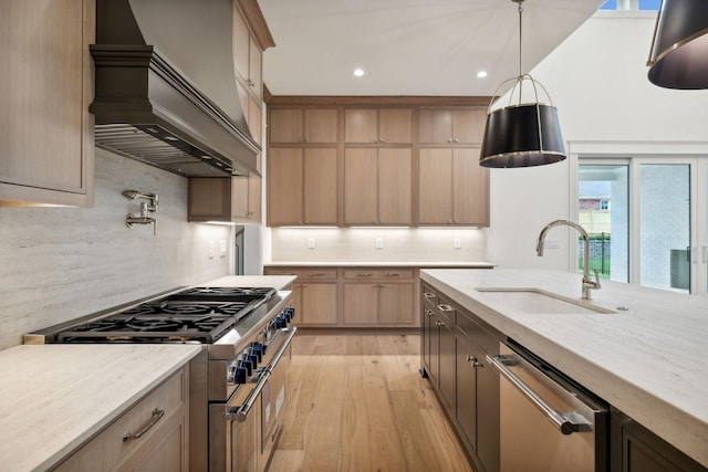 kitchen with custom exhaust hood, light hardwood / wood-style floors, stainless steel appliances, light stone countertops, and sink