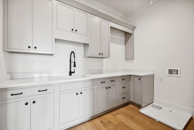 kitchen featuring sink, gray cabinetry, light wood-type flooring, and ornamental molding