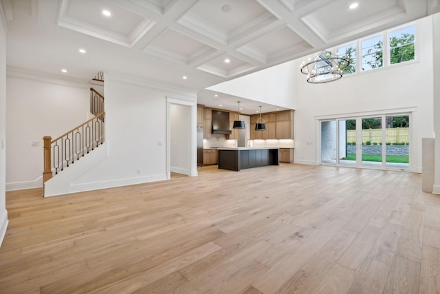 unfurnished living room with light hardwood / wood-style floors, a wealth of natural light, a chandelier, and beam ceiling